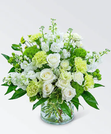 Roses, carnations, mums, assorted foliage and more in a clear glass vase