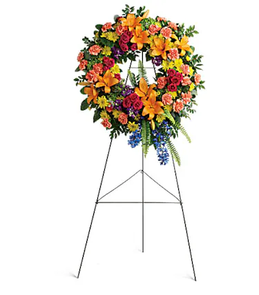 Sympathy wreath of flowers in a rainbow of colors presented on an easel