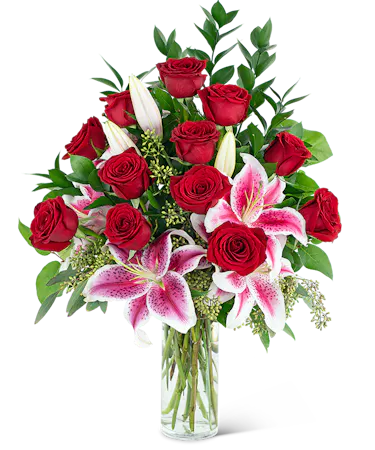 Red roses, stargazer lilies and greenery in a clear glass vase