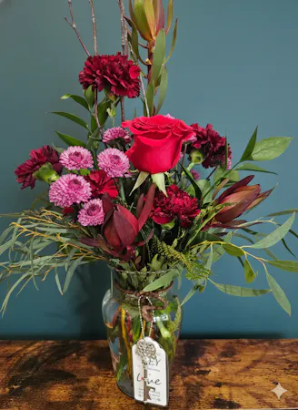Deep red flowers with textural greenery and a vintage key