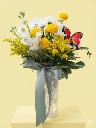 A light up acrylic vase decorated with daisies filled with stock, white daisies, yellow buttons 