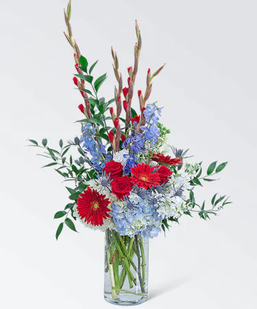 Red, white and blue flowers in a clear vase