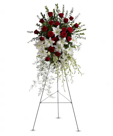An Easel spray designed with red roses, white dendrobium orchids, lilies  and assorted greenery