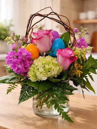 Featuring roses, hydrangea, and festive Easter eggs in awillow-arched vase. 