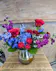 Our Midnight Romance features dramatic red roses, royal blue hydrangeas, and fragrant purple blooms in a reflective black vase