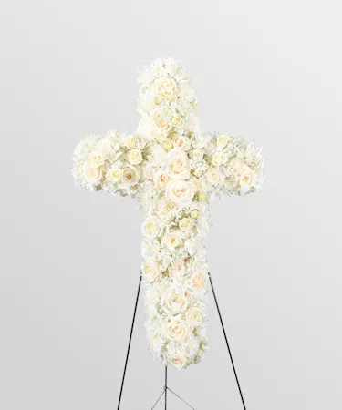 white roses and carnations on a standing cross spray