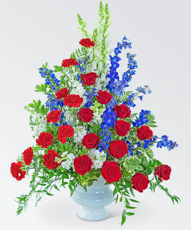 Patriotic display of red, white and blue flowers in a white urn