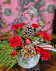 a white basket filled with winter greens, pinecones, red carnations, mini carnations