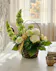 A wicker basket Featuring Bells of Ireland, white roses, and festive gold accents