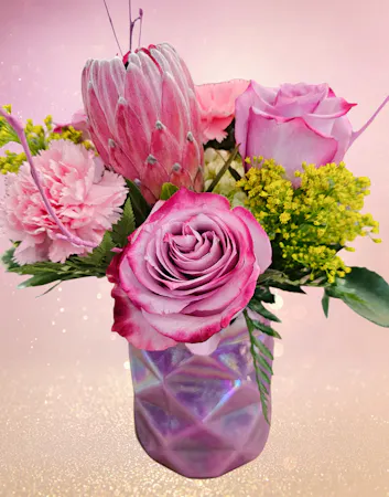Pink protea, lavender roses, pink carnations in a geometric pink cylinder