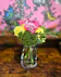 Yellow carnations & lavender roses are set off by green hypericum in a clear vase