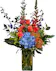 Blue delphinium, orange roses, pincusion protea, yellow solidago in a tall elegant vase