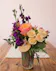 A vibrant Free Spirit rose, peach spray roses and purple stock arrangement in a reusable patterned tumbler with a bamboo lid