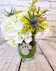 White hydrangea, roses, chrysanthemums are accented with blue eryngium and yellow solidago. Tucked into our Queen's Jewels winegass embellished with a rhinestone paw print