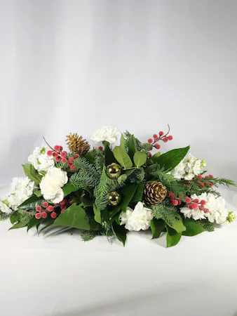 white flowers nestled in a bed of fragrant winter greens and accented with iced red berries, gold pine cones and gold ornaments