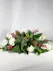 white flowers nestled in a bed of fragrant winter greens and accented with iced red berries, gold pine cones and gold ornaments