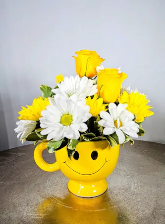 Yellow & White daisies in a smile face mug with yellow roses