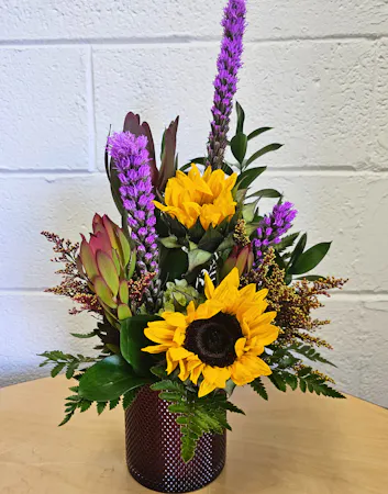 Sunflowers,liatris, fall greenery and textural accents in a red textured cylinder 