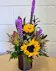 Sunflowers,liatris, fall greenery and textural accents in a red textured cylinder 