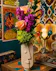 . This unique sculptural face vase overflows with vibrant coral roses, purple stock, and neon greens&mdash;the perfect gift for dreamers and design lovers.