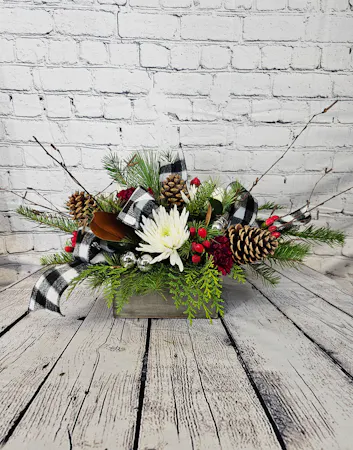 A rustic wooden container, add fragrant winter greens, burgundy carnations, white chrysanthemums, black & white ribbon and silver balls